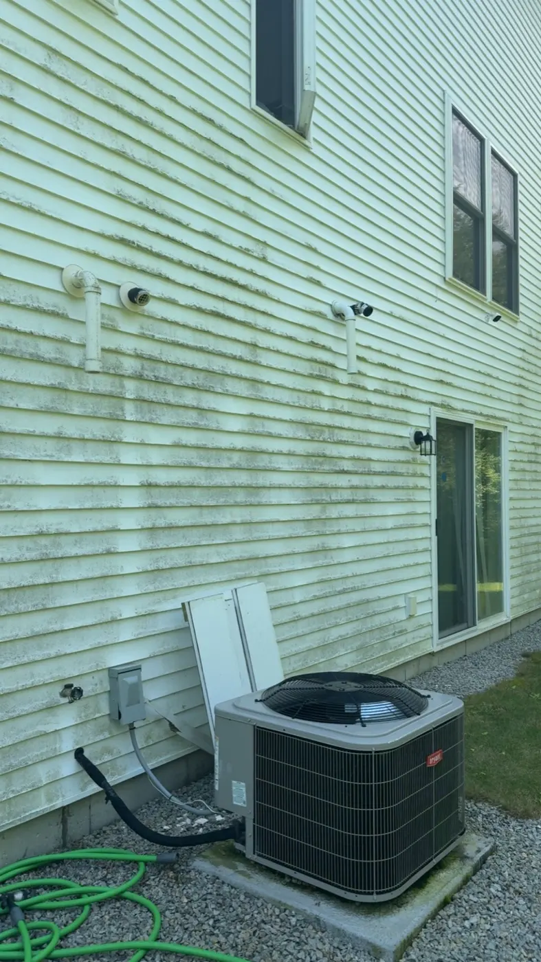 Before: white vinyl siding covered in green algae next to an AC unit